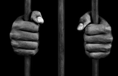Hands of a prisoner on prison bars