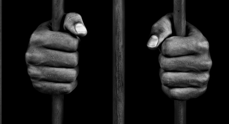 Hands of a prisoner on prison bars